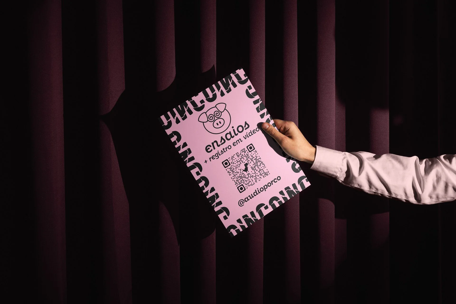Pink rehearsal flyer held against a curtain