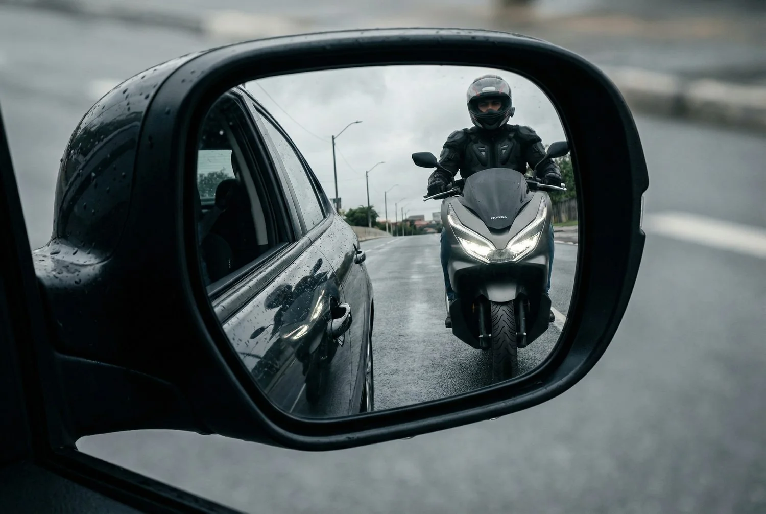 Scooter rider seen in a car side mirror
